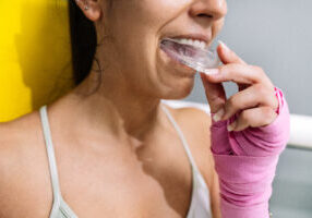 Midsection of a female athlete putting on a mouth guard in boxing training in a ring.