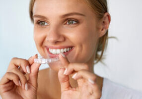 Teeth Whitening. Beautiful Smiling Woman With White Smile, Straight Teeth Using Teeth Whitening Tray. Girl Holding Invisible Braces, Teeth Trainer. Dental Treatment Concept. High Resolution Image